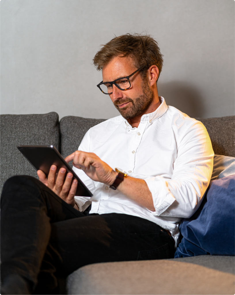 En mand i hvid skjorte, der bruger sin tablet, mens han har Luxreaders skærmbriller på