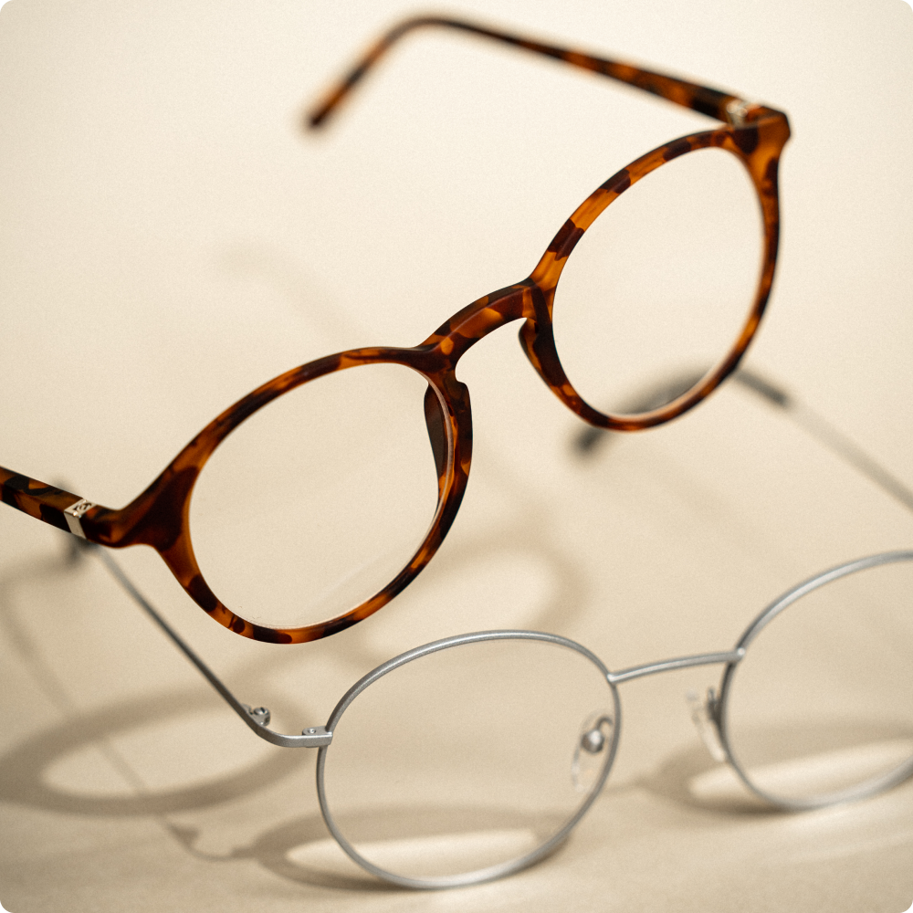 To runde læsebriller står ved siden af hinanden på et bord